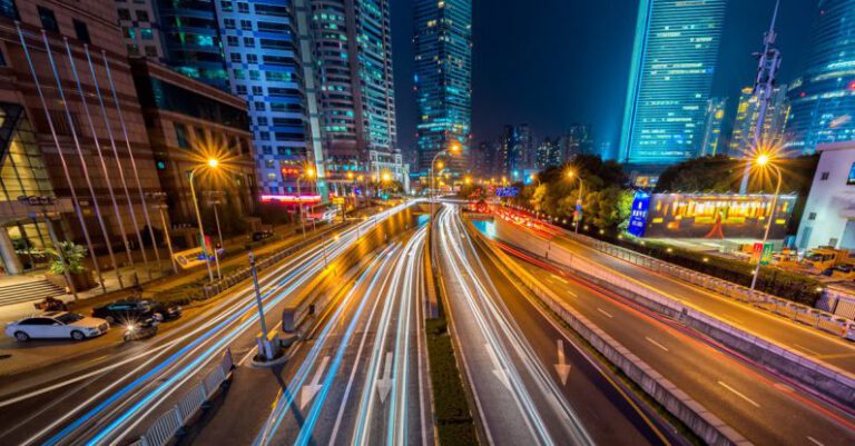 Smart Cities - Timelapse Photography of Vehicle on Concrete Road Near in High Rise Building during Nighttime