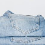 Qualities - Pile of denim pants of different shades of blue placed on white shelf