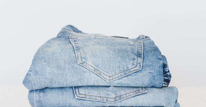 Qualities - Pile of denim pants of different shades of blue placed on white shelf