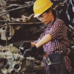 Skills - Woman Wears Yellow Hard Hat Holding Vehicle Part